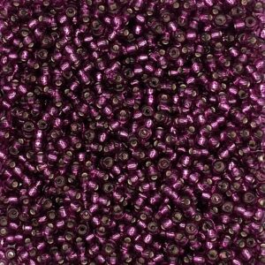 Purple seed beads scattered in dense arrangement.
